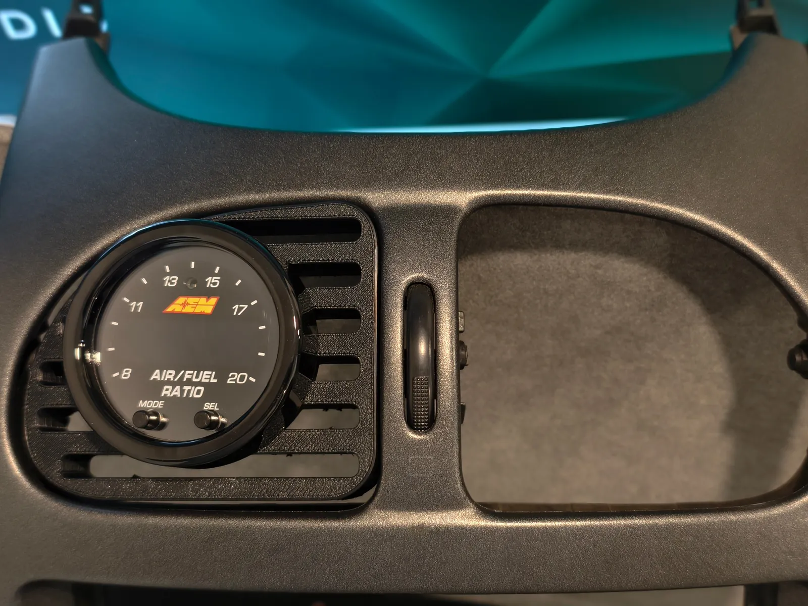 Soporte de manómetro impreso en 3D montado en el embellecedor de consola de un Peugeot 206, con un manómetro AEM de relación aire/combustible encajado en él